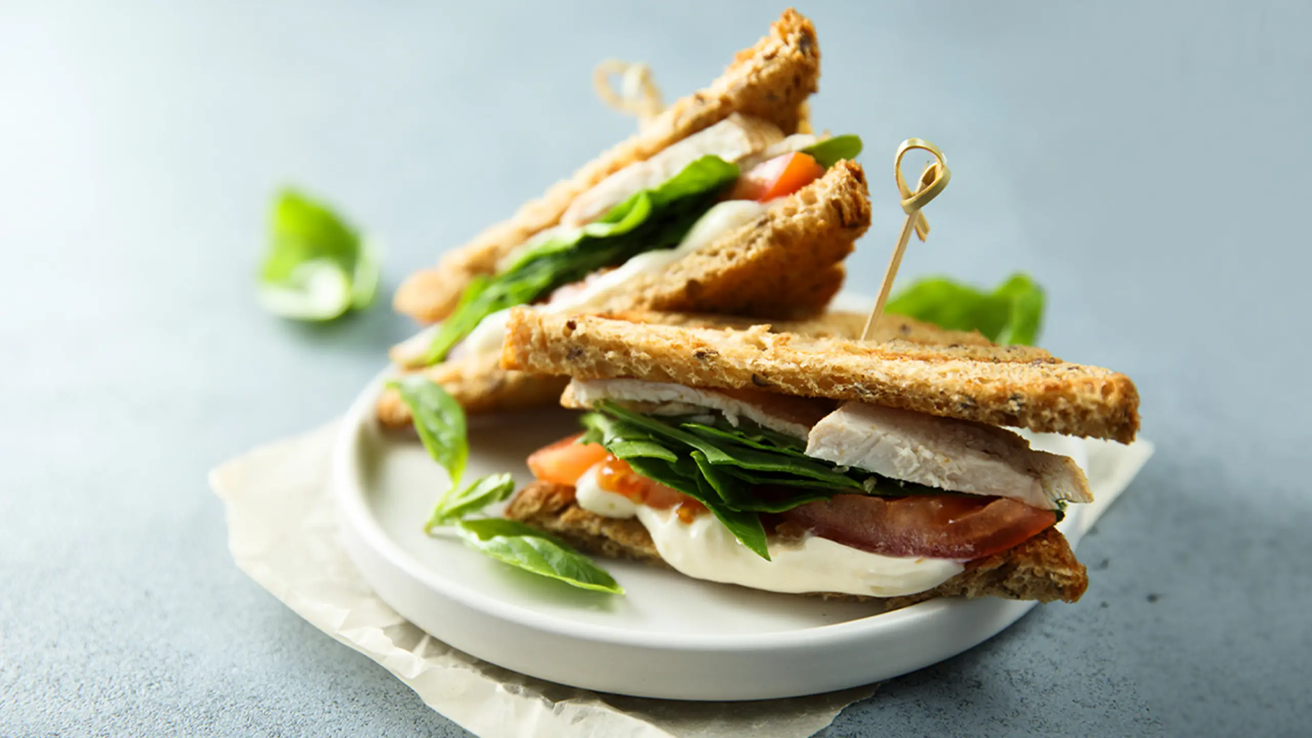 to clubsandwich på lille rund tallerken på blåt bord